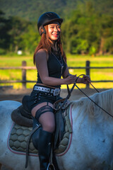 Fototapeta premium Vertical sexy Asian cowgirl riding on horse in ranch