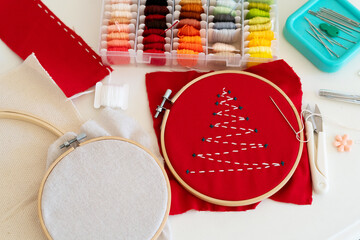Crafting an elaborate embroidery design on red fabric with colorful threads and sewing tools on a workspace