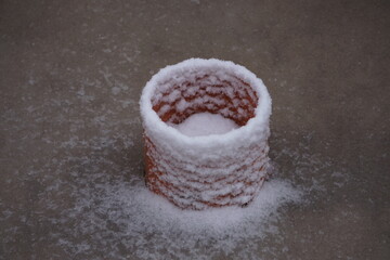 Plastikowa rura w domu, częściowo pokryta śniegiem, podczas etapu montażu. Surowa budowa i biały puch podkreślają zimowe warunki prac instalacyjnych.