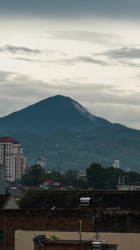 Vertical video - Timelapse of clouds calmly rolling over the mountain in the afternoon