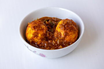 Spicy Egg Curry (Anda Curry or Dim Bhuna) served in a white ceramic bowl, featuring boiled eggs and rich gravy. Delicious and traditional Bengali food from South Asia, ready to eat.