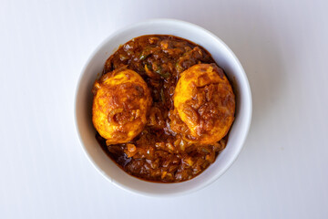Delicious, spicy, and savory traditional Bengali Anda Curry or Dim Bhuna (Egg Curry), an authentic South Asian food, served hot in a clean white ceramic bowl. Cuisine concept. Top view.
