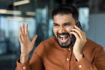 Young stressed indian man expressing anger and frustration while having an intense phone...
