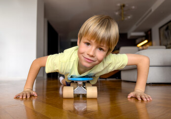 Smiling blond boy of 6 years old playing on a scooter at home.