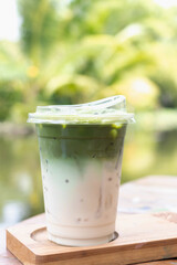 Iced matcha latte with layered milk and green tea, refreshing outdoor beverage with ice and cup lid