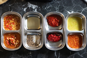 Spicy condiment selection with chili pastes, sauces, oil and salt pepper mix creating bold vibrant flavors, Korean style.