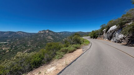 Curved Road Overlooking Stunning Mountain Landscape Under Clear Blue Sky
