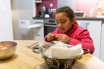 Young girl enjoying a delicious fried chicken dinner in a modern kitchen, focusing on the concepts of childhood, eating, and family meals at home