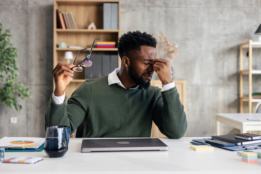 Young man experiencing stress and headache at office workspace