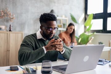 African american man concentrating on work using laptop in office