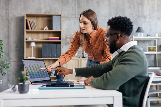 Business colleagues analyzing data on laptop in office