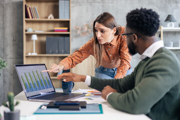 Business colleagues analyzing data on laptop in office