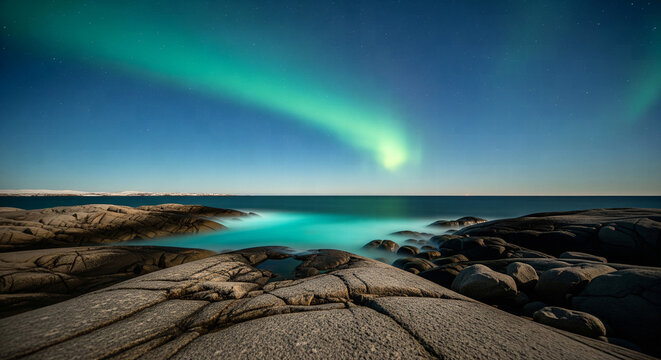 Bright Green Aurora Arc Over a Rocky Shoreline with Turquoise Glowing Water