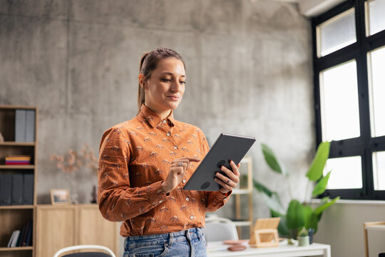 Professional woman using digital tablet in modern office - Powered by Adobe
