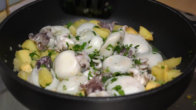 Seppie, patate cipolla e prezzemolo cuociono nella pentola e il cuoco mescola gli ingredienti