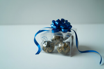 Elegant Transparent Tea Ball Pack Tied with Blue Festive Ribbon Against White Background