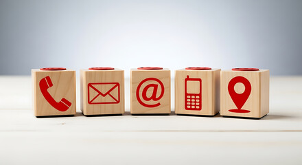 Contact methods depicted on wooden blocks including phone email and location icons on white surface