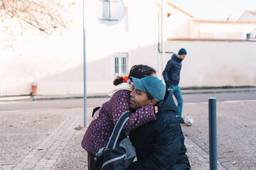 Father and daughter affectionately hugging outdoors, sharing a tender moment of love and connection on a sidewalk while other people pass by