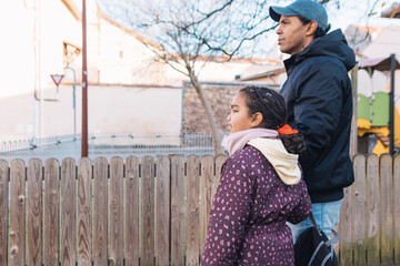 Father and his preteen daughter are observing their surroundings on a sunny day during an outdoor walk, showcasing family connection and a shared experience