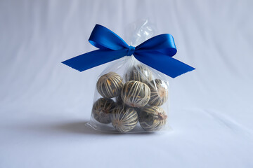 Clean Transparent Plastic Pack of Dry Tea Balls with Blue Festive Ribbon on White Background