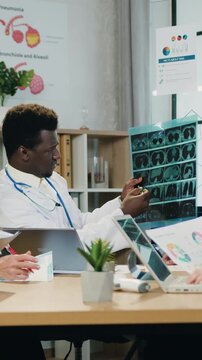 Attractive successful experienced modern multiethnic medical workers gathering together in workroom and consulting about patient's disease diagnostic using x-ray scan