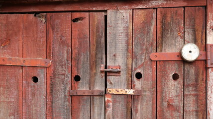 Barn plank doors with a deadbolt, distressed plank surface and rusting metal fasteners, barn texture background, closed doors with beautiful texture of the outbuilding close-up as a design banner
