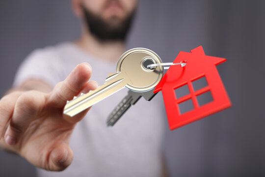 Close-up of a hand holding keys with a house-shaped keychain, symbolizing home ownership, real estate and investment. Perfect for property relat - Powered by Adobe