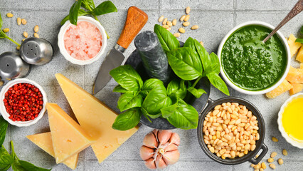 Ingredients for making Pesto sauce: basil, parmesan, nuts, lemon and spices. On a gray stone...