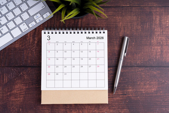 March 2026 desk calendar with keyboard and pen on wooden workspace.
