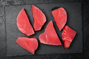 Raw fresh tuna fish steaks set. On black slate background. Close up, Top view.