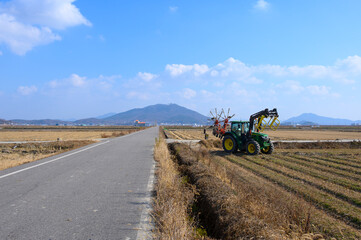 A view of Ganghwado's rice fields and a circular baler. Autumn rice fields after harvest. A view of Gyodongdo Island in Ganghwado. Korean traditional rice farming.
