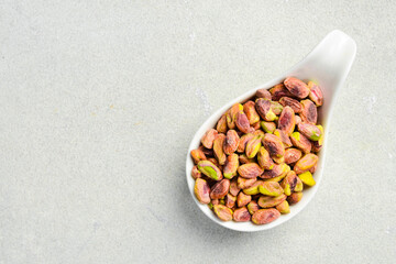 White ceramic bowl with peeled pistachio kernels. Nuts ready to eat. Top view. On a white background.
