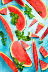 Watermelon background. Sliced pieces of ripe watermelon on a blue stone background, top view.