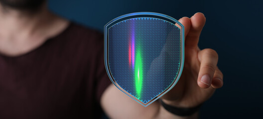 A close up shot of a person holding a digital shield representing security and protection of data with digital lights and lines over