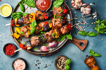 Kebabs - grilled meat skewers, shish kebab with vegetables on a plate. On a concrete old table. Top view.