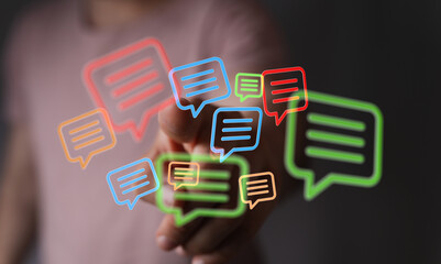 Close up of hand interacting with digital chat bubbles, representing online communication and tech solutions.