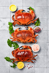 Boiled red crabs seasoned with lemon, sea salt and parsley on a plate ready to eat. On a gray kitchen background.