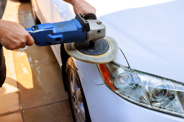 Person is buffing front of light colored car with polishing tool under work day