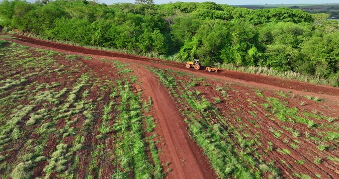 Tractor with agricultural implement plowing land next to riparian forest