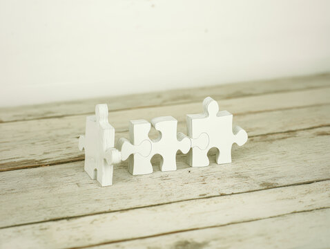 White puzzle piece row on wooden table evoking teamwork and connection in minimalist rustic setting calm