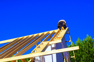 Worker is climbing framework of joists roofing adding rafters to roof