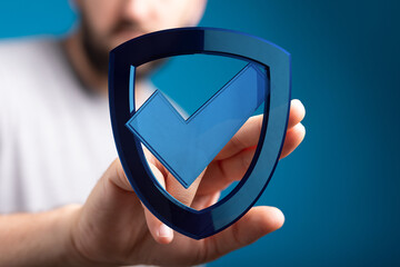 Hand holding a shield icon with a check mark, representing protection, security, and approval....