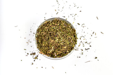 Fragrant dried herb for mint tea lies in and around a glass bowl.