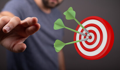 Close-up of a hand reaching for a dartboard with three darts in the center, representing focus and...