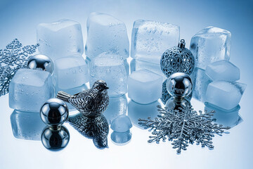 An elegant still life in cool tones with clear ice cubes, silver Christmas tree baubles, a...