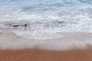 Coastal scene displaying shore waves and wet sand, natural background