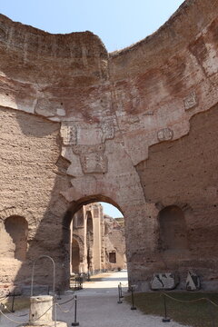Baths of Caracalla, A towering, curved section of the Roman bath ruins, featuring a massive central archway leading to the outer complex