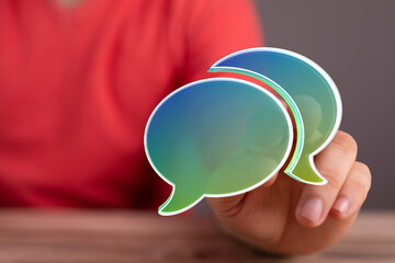 Hand holding speech bubbles, symbolizing communication, conversation, social media, discussion, and dialogue. Representing ideas, thoughts, and