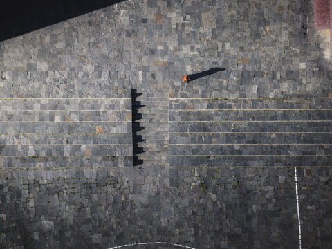 Aerial view of a solitary figure casting a long shadow across the gray stone courtyard of Haa Dzong, the historic fortress, Haa, Bhutan.