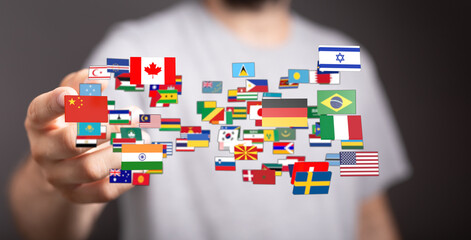 Conceptual image of a person's hand surrounded by flags of various countries. Representing...
